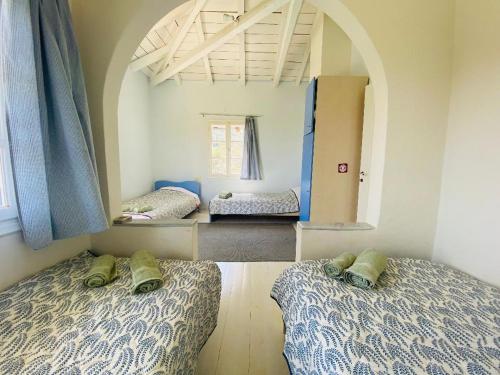 a room with two beds and an arched window at Cottage with private boat & pool in Poros