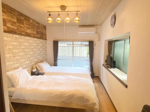 a bedroom with two beds and a brick wall at Rapport Kukomae 207 in Fukuoka