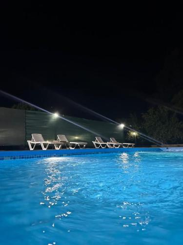 - un groupe de chaises à côté de la piscine la nuit dans l'établissement Brothershomesbungalow, à Bahtılı