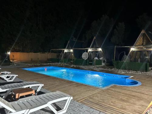 a swimming pool at night with two lounge chairs next to it at Brothershomesbungalow in Bahtılı