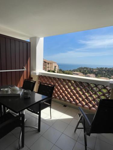 Un balcón con mesa y sillas y vista al mar. en Cap Esterel - Charmant T2 climatisé vue mer 4/5 pers - Piscine - Parking, en Agay - Saint Raphael