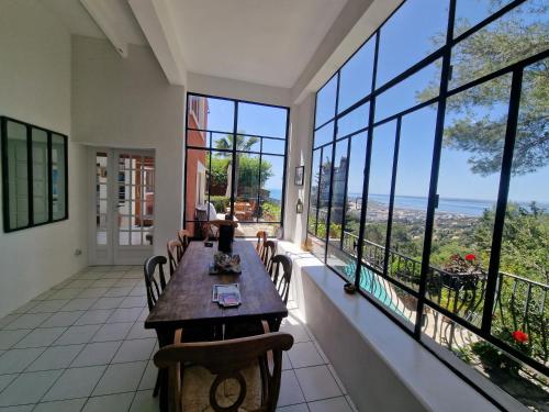 a room with a table and chairs and large windows at Villa Clarté Sète in Sète