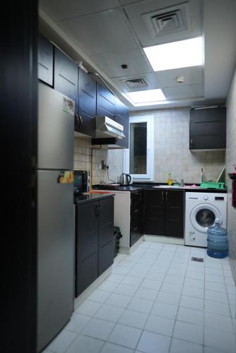 a kitchen with black cabinets and a white tile floor at Women Only Hostel near Burjuman Metro exit 4 in Dubai