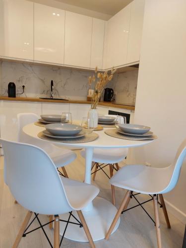 a white kitchen with a table and chairs at Harmony Pearl Apart in Rogowo