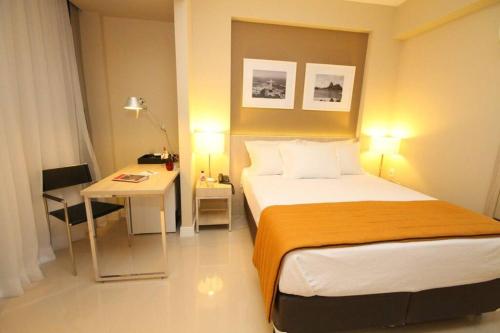 een slaapkamer met een bed, een tafel en een bureau bij Suíte completa na Barra da Tijuca, Link Stay in Rio de Janeiro