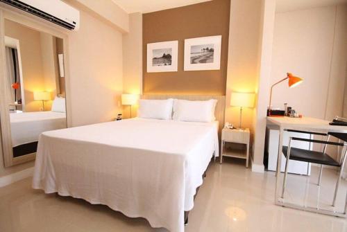 een slaapkamer met een groot wit bed en een bureau bij Suíte completa na Barra da Tijuca, Link Stay in Rio de Janeiro