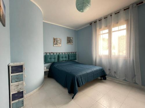 een blauwe slaapkamer met een bed en een raam bij Villa Silvana in Mazara del Vallo