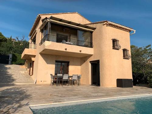 une maison avec un balcon, une table et des chaises dans l'établissement Villa 8 pers Aux Issambres Vue Mer & Piscine chauffée, à Roquebrune-sur Argens