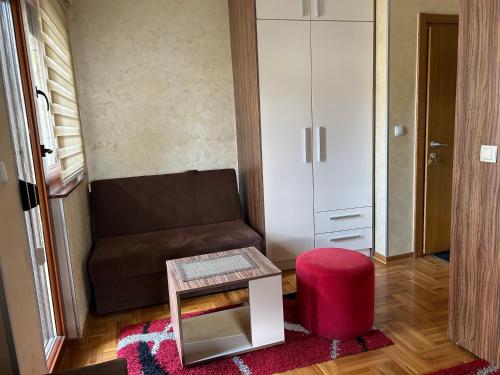 a living room with a couch and a red stool at Zlatiborski konaci- apartman Katarina in Zlatibor