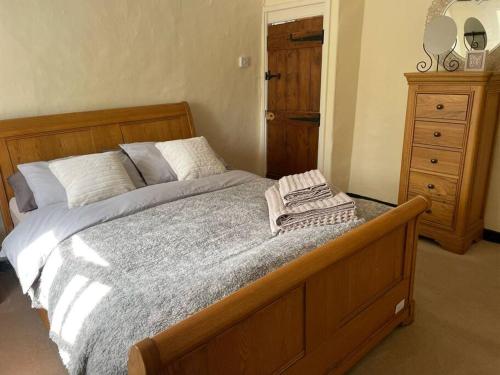 a bedroom with a wooden bed with a wooden dresser at Cosy Daffodil Cottage in Eythorne
