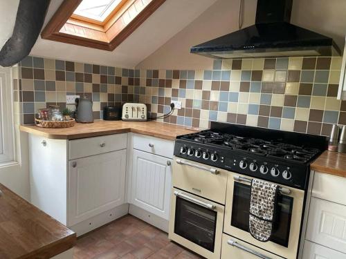 a kitchen with a stove top oven in a kitchen at Cosy Daffodil Cottage in Eythorne