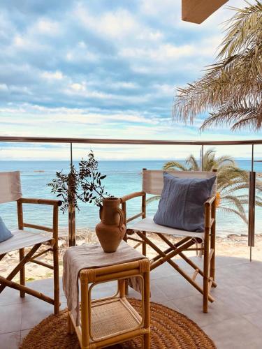 a patio with chairs and a vase on a table at Attico fronte mare Espardell19 Es Pujols in Es Pujols