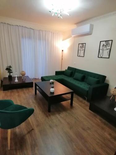 a living room with a green couch and a table at Anastasia's Apartment ΛΑΥΡΙΟ in Lávrion