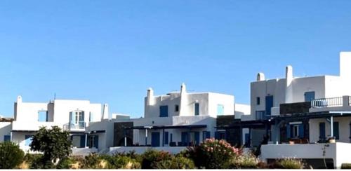 rząd białych budynków z niebieskim niebem w tle w obiekcie Villa Galano PAROS GREECE w mieście Ambelas