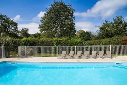 a swimming pool with chairs and a fence at Magnificent French Country House with Private Heated Pool & Gardens in Quettreville-sur-Sienne
