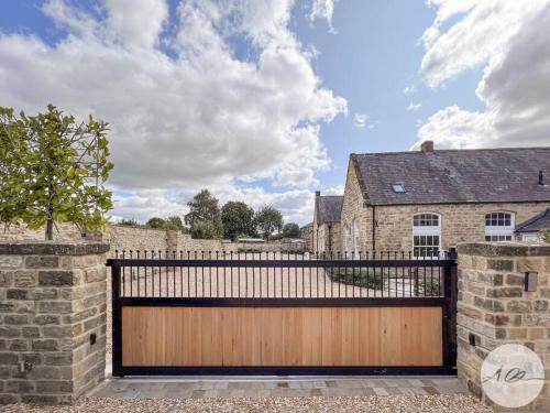 a wooden gate in front of a brick house at Exceptional Holiday Home 7 in Pickering with Hot Tub in Pickering