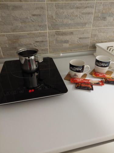 a coffee maker and two cups on a counter at Sobe Tanja in Subotica