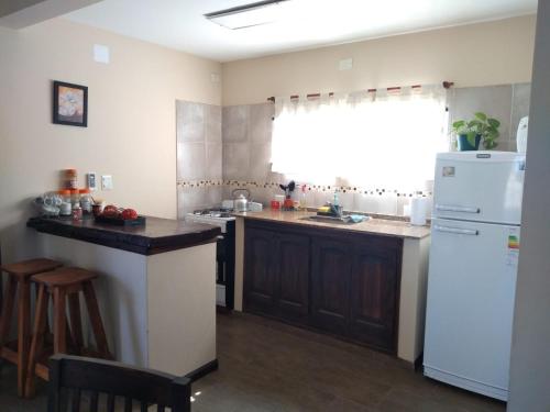 een keuken met een witte koelkast en een wastafel bij EL BAGUAL DE MONTE in San Miguel del Monte