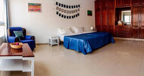 een slaapkamer met een bed, een stoel en een tafel bij Mantenha ApartHotel in Praia