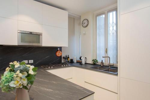 a kitchen with white cabinets and a black counter top at Lussuoso Pentalocale in CityLife in Milan