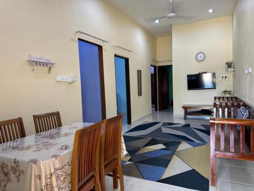 a dining room with a table and a tv in a room at Homestay Haji Noor in Tanah Merah