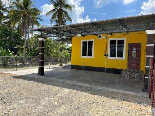 a yellow building with palm trees in the background at Homestay Haji Noor in Tanah Merah