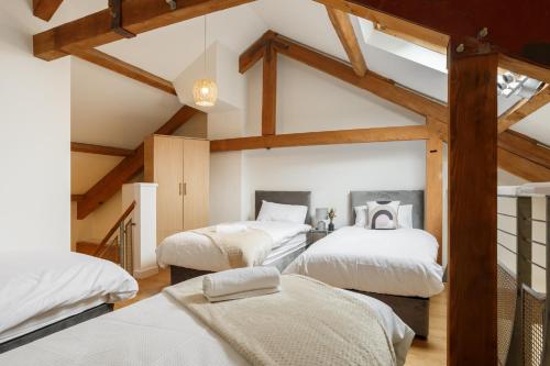 three beds in a room with wooden beams at Cozy Downtown Loft in Bradford in Bradford