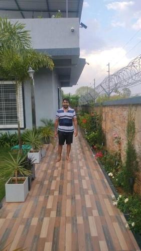 a man is standing on a wooden walkway at 2 bhk with private pool in Thūr