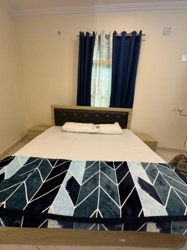 Ce lit se trouve dans un dortoir doté de rideaux bleus. dans l'établissement Ved Vatika Homestay, à Faizābād