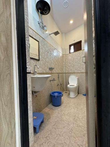 La salle de bains est pourvue d'un lavabo et de toilettes. dans l'établissement Ved Vatika Homestay, à Faizābād