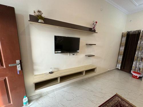  Il comprend un salon doté d'une télévision murale à écran plat. dans l'établissement Ved Vatika Homestay, à Faizābād