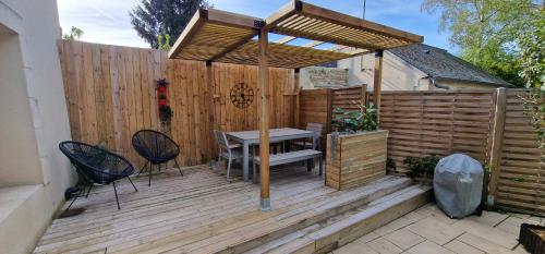 drewniany taras ze stołem i drewnianym płotem w obiekcie Gîte 4 personnes avec piscine et bain nordique proche des plages du débarquement w mieście Le Manoir