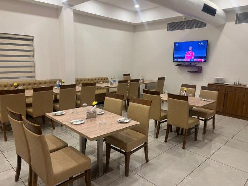 comedor con mesas y sillas y TV de pantalla plana en Hotel Abaam Neil, en Alleppey