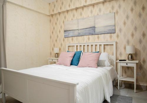 a bedroom with a white bed with pink and blue pillows at Torre Opus 31 - Apto.605 in Santo Domingo