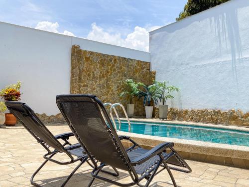 2 sillas sentadas junto a una piscina en Exclusiva casa de dos pisos con piscina privada, en Cali