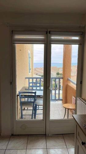 une cuisine avec des portes s'ouvrant sur une terrasse avec une table. dans l'établissement Appartement avec vue sur la mer, à Fleury