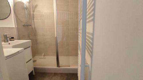 une salle de bain blanche avec une douche et un lavabo dans l'établissement T2 résidence avec piscine et tennis, à Bidart