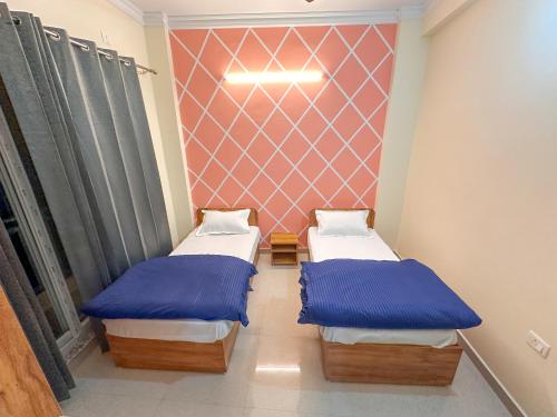 2 aparte bedden in een kamer met een muur bij Adi Yoga Ashram in Rishīkesh