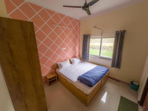 een kleine slaapkamer met een bed en een raam bij Adi Yoga Ashram in Rishīkesh