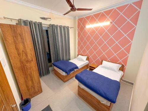 een kamer met 2 bedden en een muur bij Adi Yoga Ashram in Rishīkesh