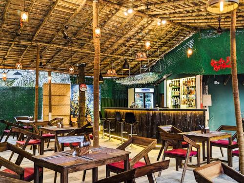 um restaurante com mesas e cadeiras de madeira e um bar em Seaside Serenity Resort em Mandrem