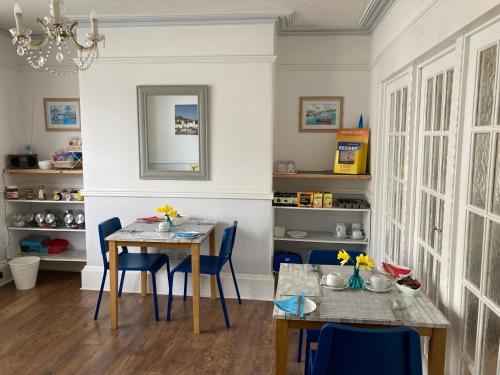 a dining room with a table and blue chairs at Braemar in Weymouth