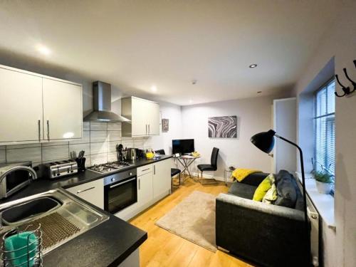 a kitchen and living room with a couch and a table at Suitely Stays Patio Apartment in Cheltenham