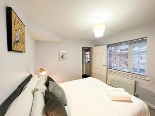 a bedroom with a large white bed and a window at Suitely Stays Patio Apartment in Cheltenham