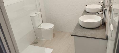 a white bathroom with a toilet and a sink at Apartamentos Don Pepe in Torremolinos