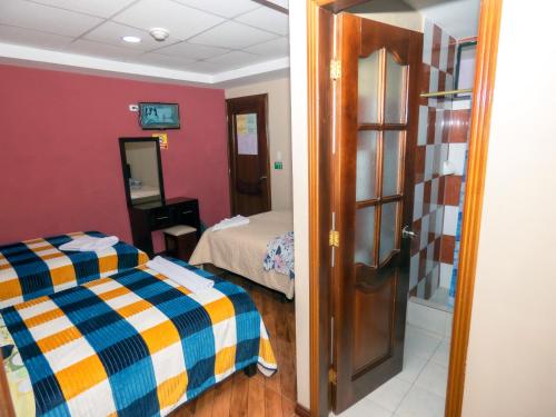 a room with two beds and a door to a bedroom at Hotel El Ejido in Quito