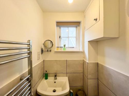 a small bathroom with a sink and a window at Suitely Stays Berkeley Apartment 5 in Cheltenham