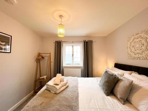 a bedroom with a large white bed with a window at Suitely Stays Berkeley Apartment 5 in Cheltenham