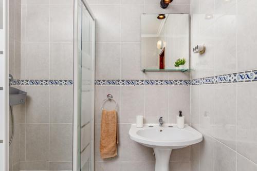 ein weißes Bad mit einem Waschbecken und einer Dusche in der Unterkunft MADA HOUSE's II in Sesimbra