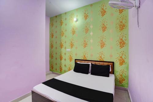 OYO Flagship Hotel Divy inn في Prayagraj: غرفة نوم بسرير مع جدار أخضر